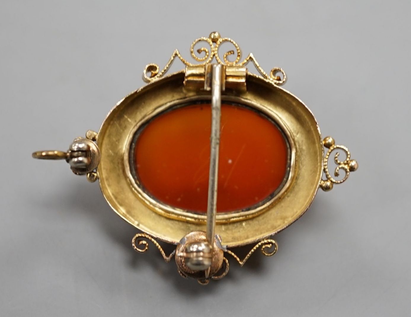 A Victorian style yellow metal and hardstone cameo set oval hardstone pendant brooch, 37mm, gross 6.9 grams.